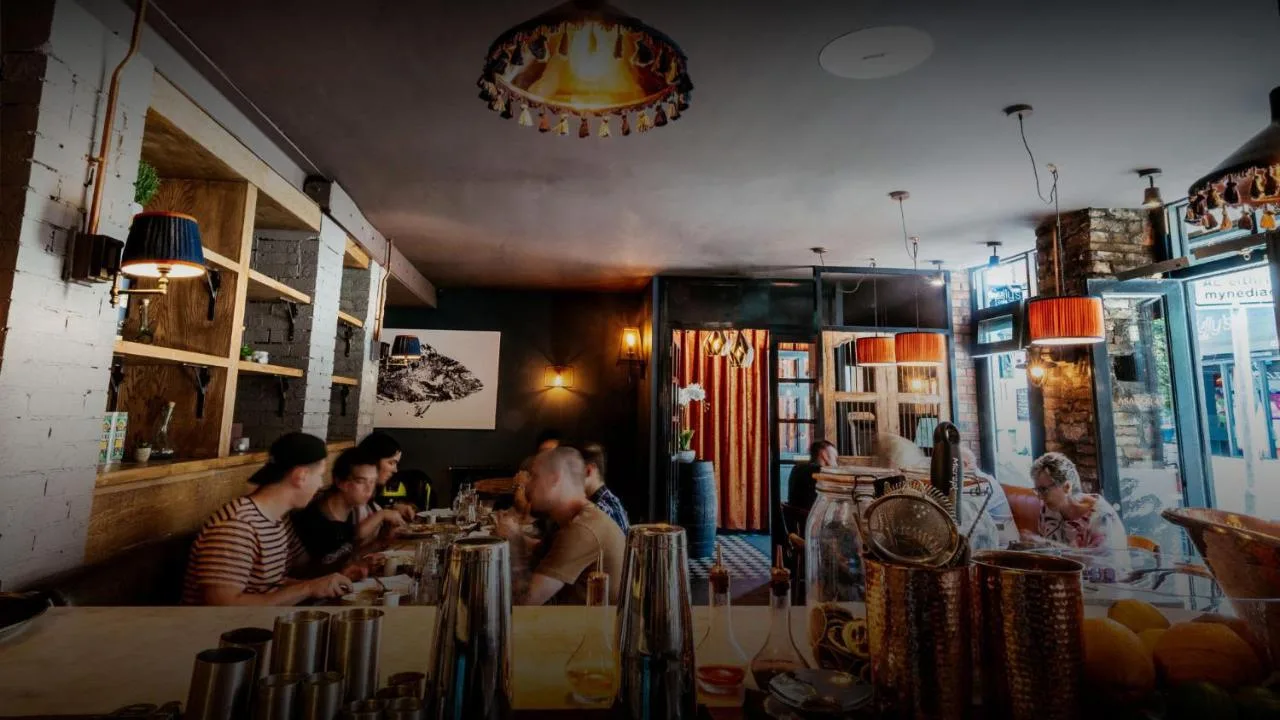 a group of people sitting at a bar in a restaurant at Parador 44 in Cardiff